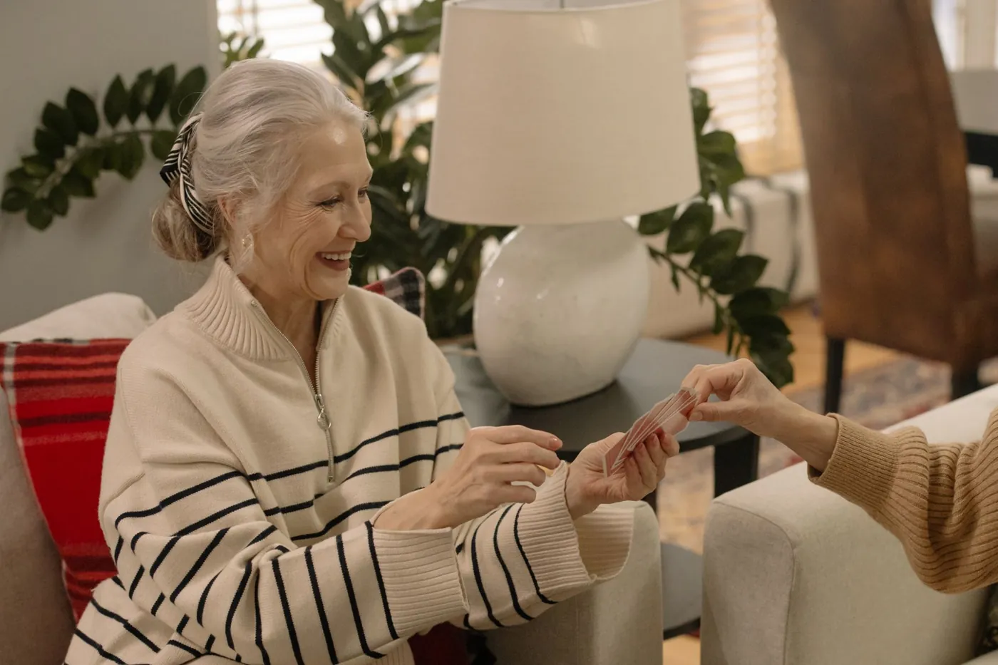 A smiling older woman holding her cards during a relaxed card game at home